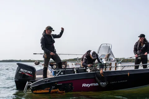 Tre personer sportfiskar från en motorbåt i den åländska skärgården.