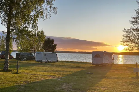 Matkailuauto pysäköitynä meren rannalle Ahvenanmaan leirintäalueella auringonlaskun aikaan.