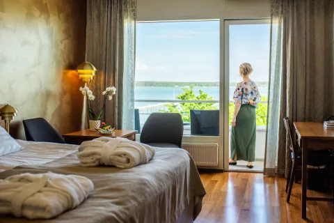 Hotellihuone merinäköalalla Ahvenanmaalla, vieras seisoo parvekkeen ovella.