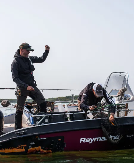 Three people sport fishing from a motorboat in the Åland archipelago.