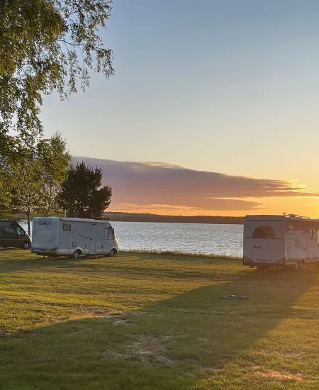 Camping vid havet med husbilar i solnedgång