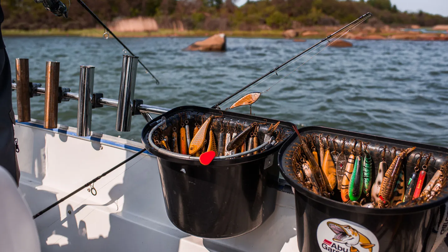 Sportfiske från båt i Ålands skärgård med spö och draglådor i förgrunden.