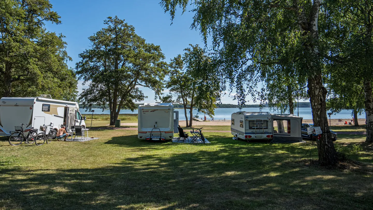Leirintäalue Ahvenanmaalla meren rannalla matkailuautoilla ja -vaunuilla