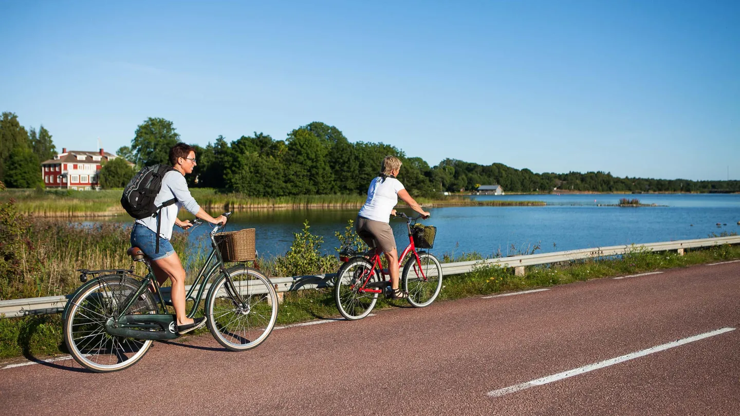 Två cyklister njuter av sommardagen vid havet på Åland – en del av Ålandsresors resepaket