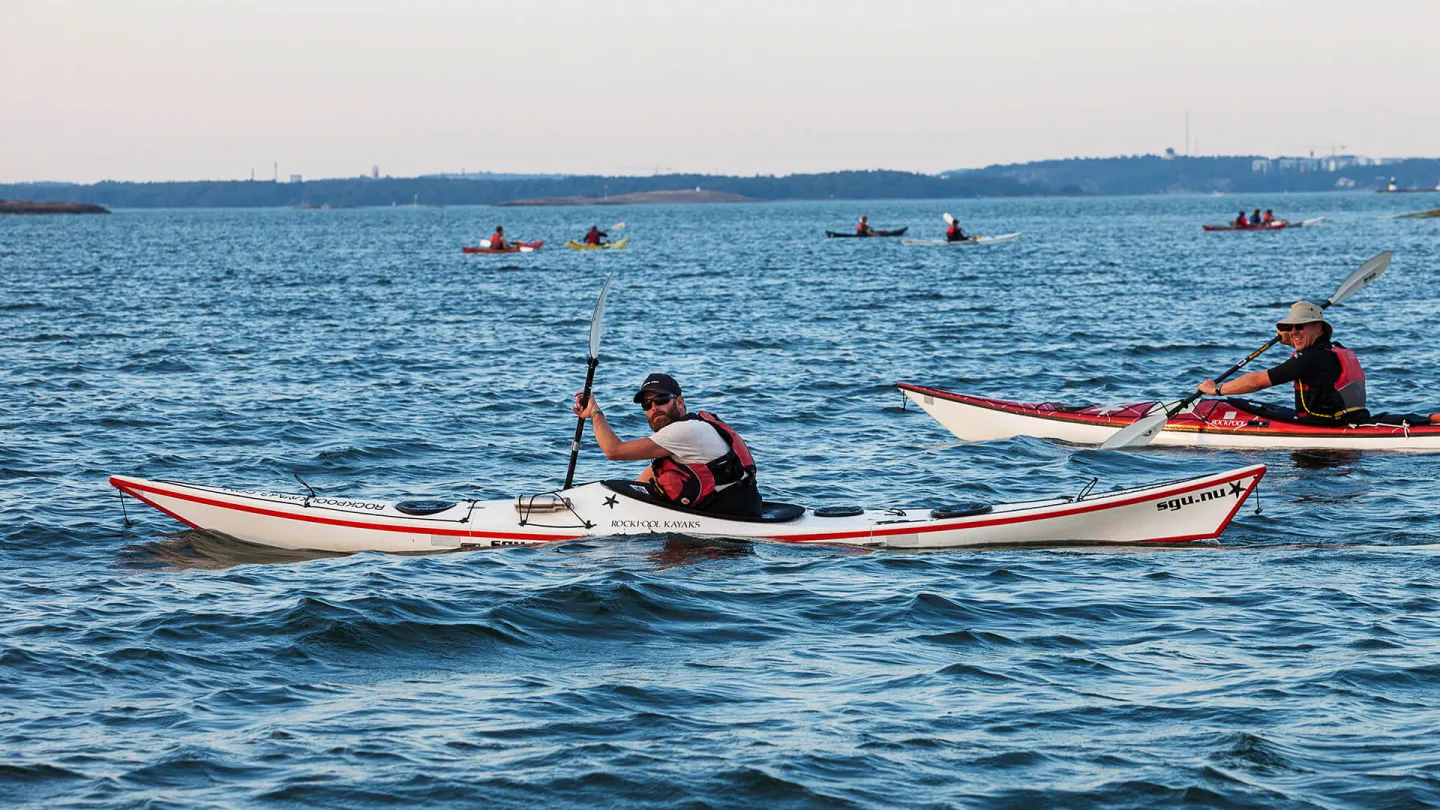 Grupp paddlar kajak i Ålands skärgård en solig dag
